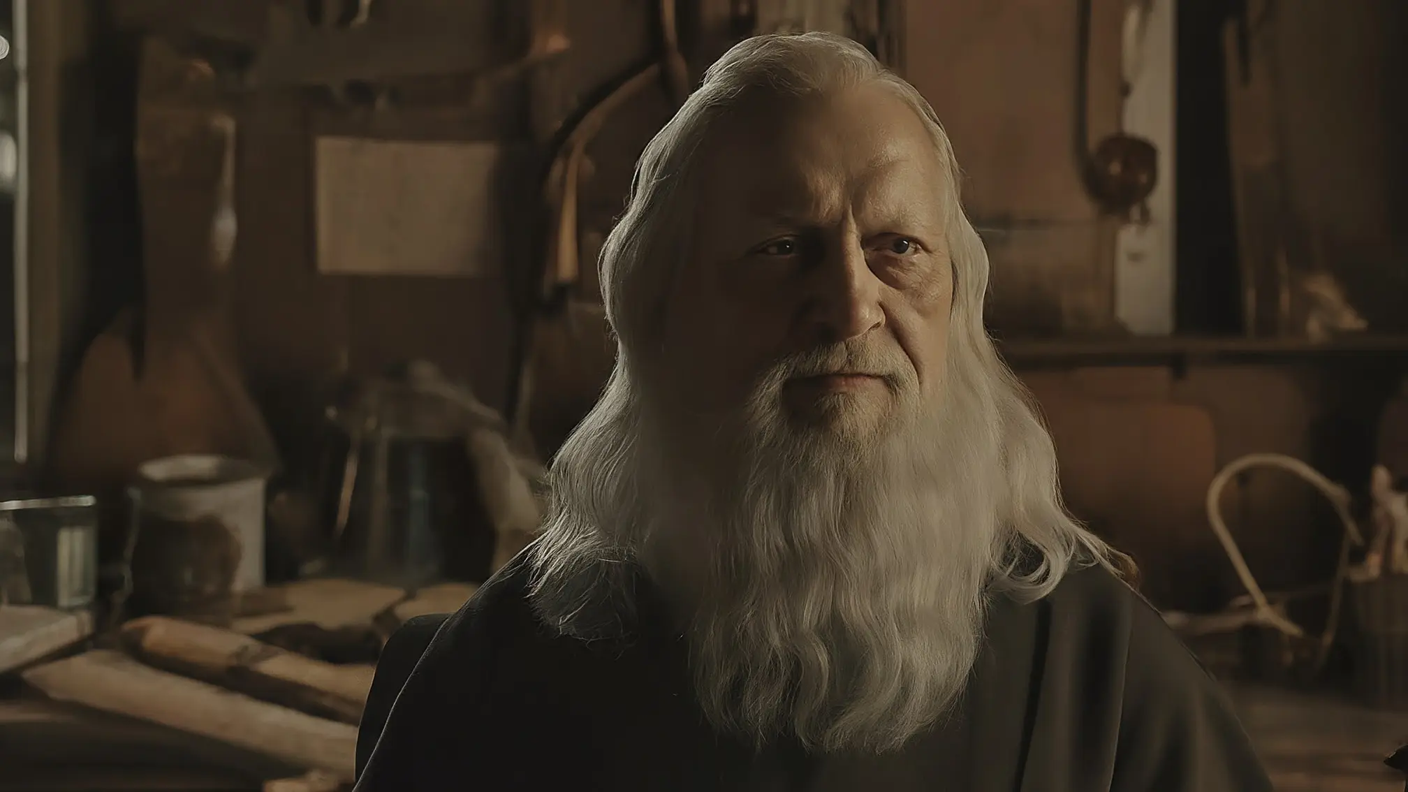 Un retrato de Leonardo da Vinci, con su característico rostro pensativo y barba entrecana, vestido con ropa oscura de época, con un fondo difuminado de un estudio con instrumentos y bocetos.